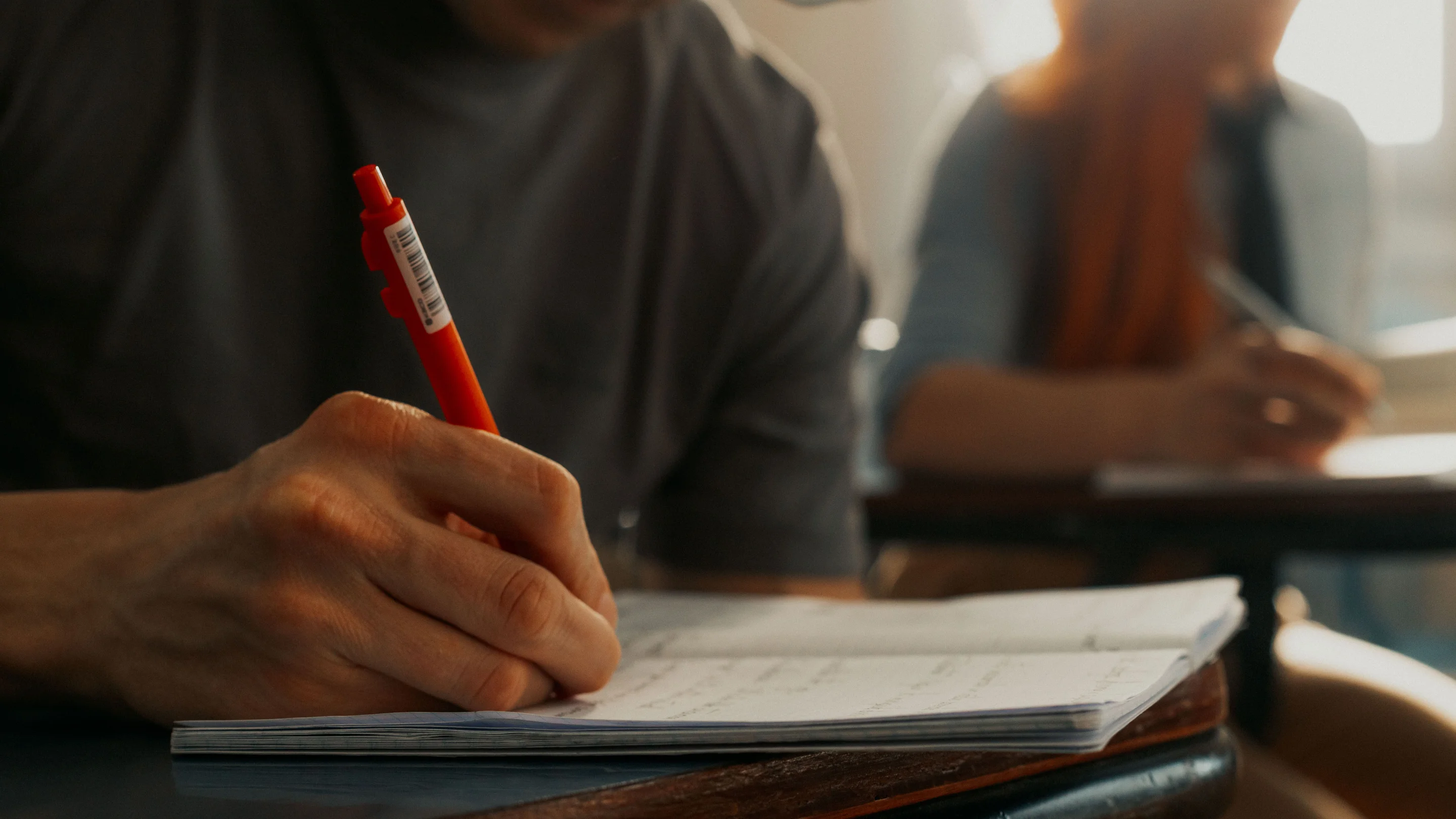 University students taking notes in notebooks during a class.