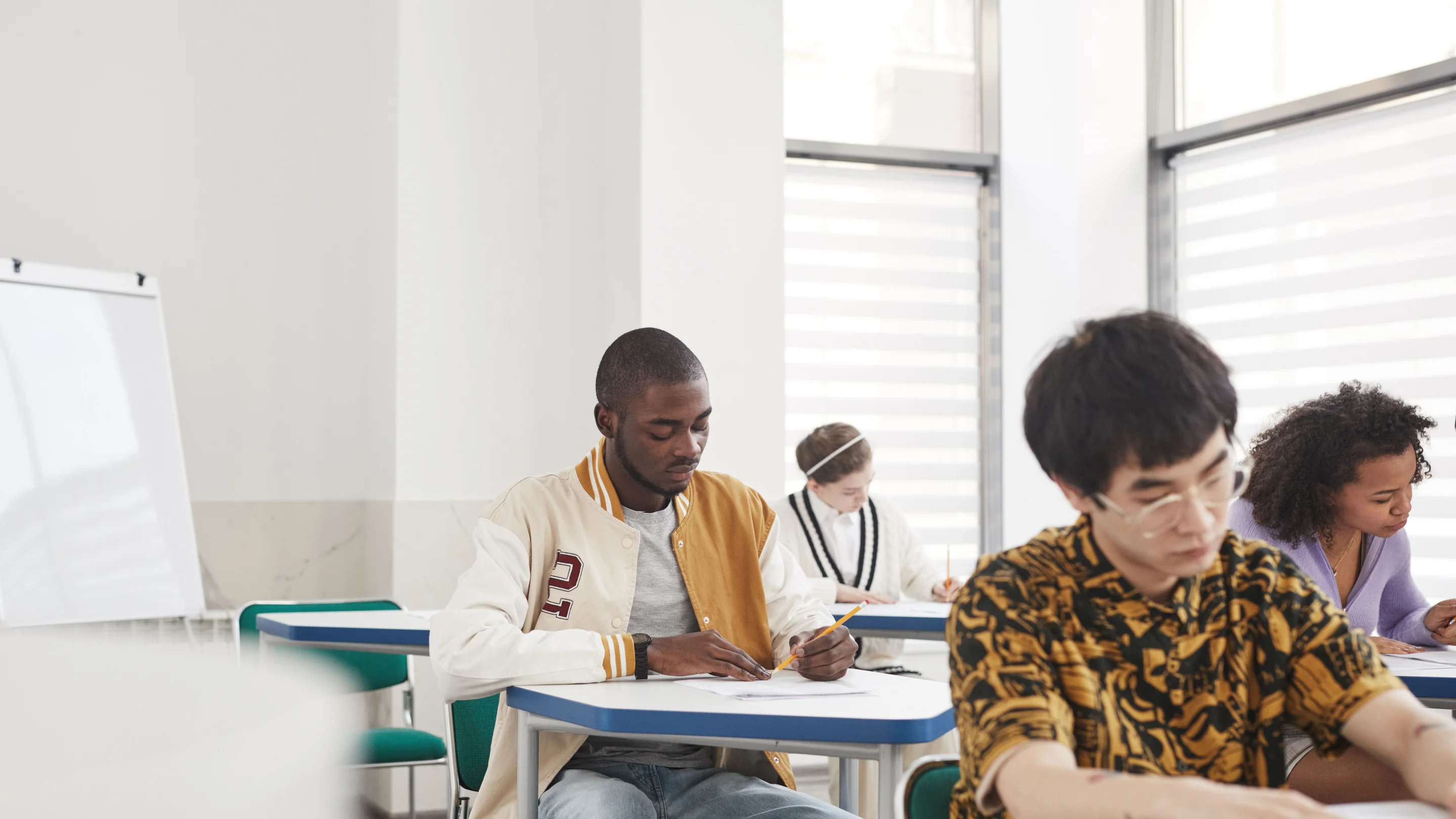 Candidates writing at desks in an exam room.
